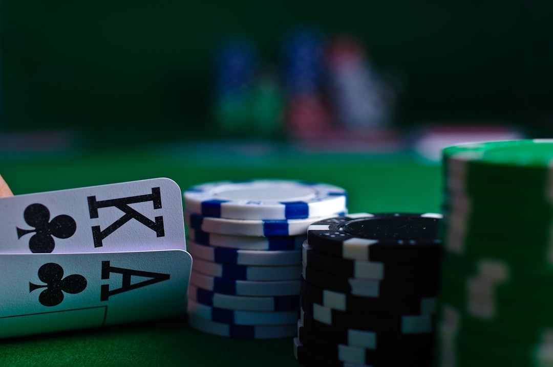 Tangan memegang kartu remi di samping tumpukan chip poker