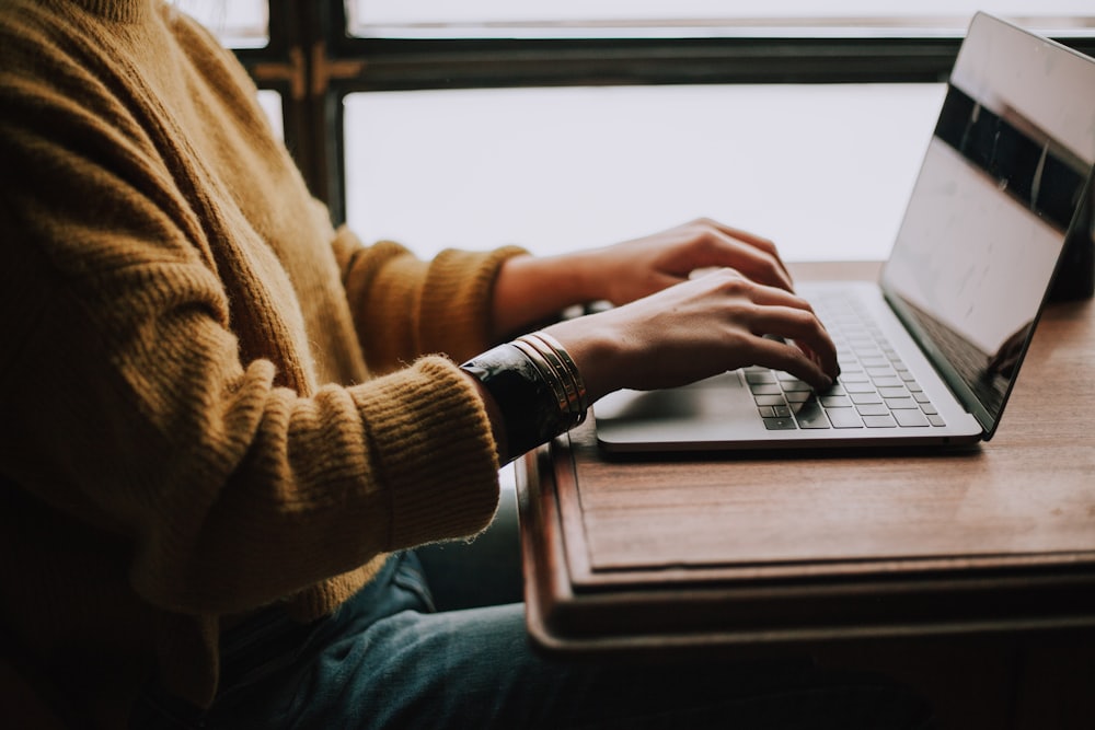 Orang duduk tenang mengerjakan sesuatu di depan laptop